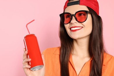 Beautiful young woman in stylish sunglasses holding tin can with beverage on pink background, closeup