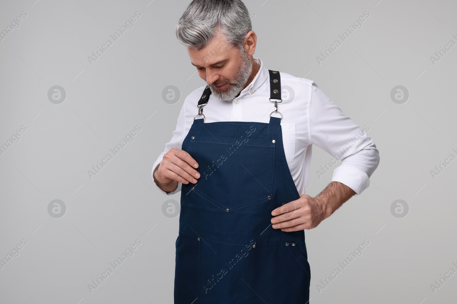 Photo of Man wearing kitchen apron on grey background. Mockup for design