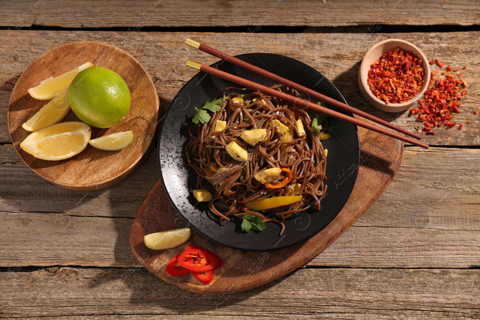 Photo of Stir-fry. Tasty noodles with vegetables and meat served on wooden table, flat lay