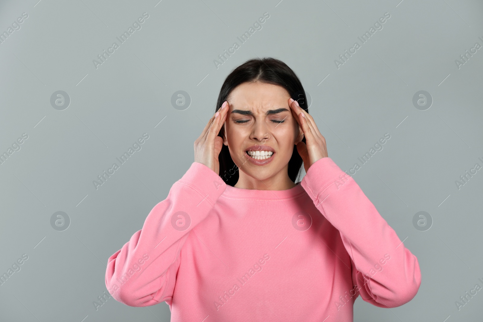 Photo of Woman suffering from migraine on grey background