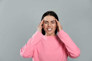 Photo of Woman suffering from migraine on grey background
