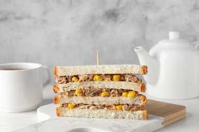 Photo of Delicious sandwich with tuna and corn on white wooden table