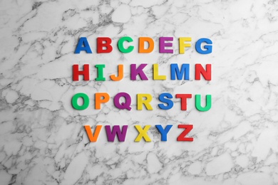 Colorful magnetic letters on white marble background, flat lay. Alphabetical order