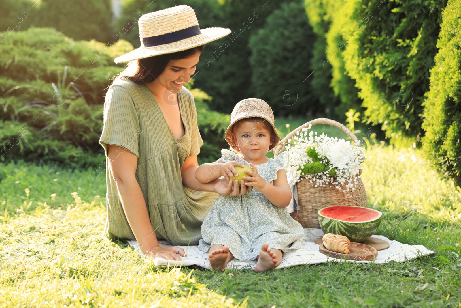 Photo of Mother with her baby daughter having picnic in garden on sunny day