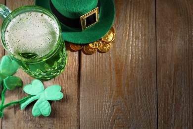 Photo of St. Patrick's day party. Green beer, leprechaun hat, gold and decorative clover leaves on wooden table, above view. Space for text