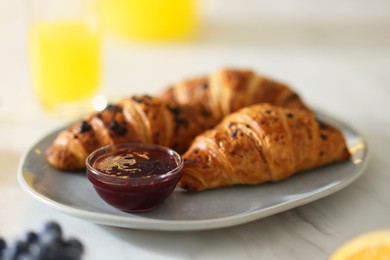 Tasty breakfast. Plate with fresh croissants and jam on white marble table, closeup