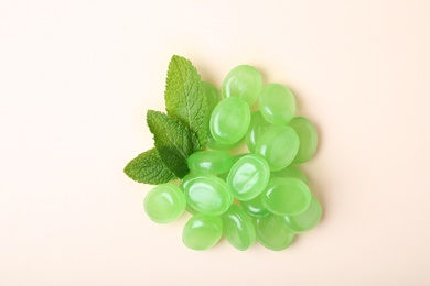 Tasty mint candies and leaves on color background, top view