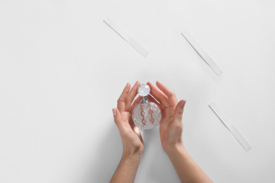 Photo of Woman with bottle of perfume on white background, top view. Space for text