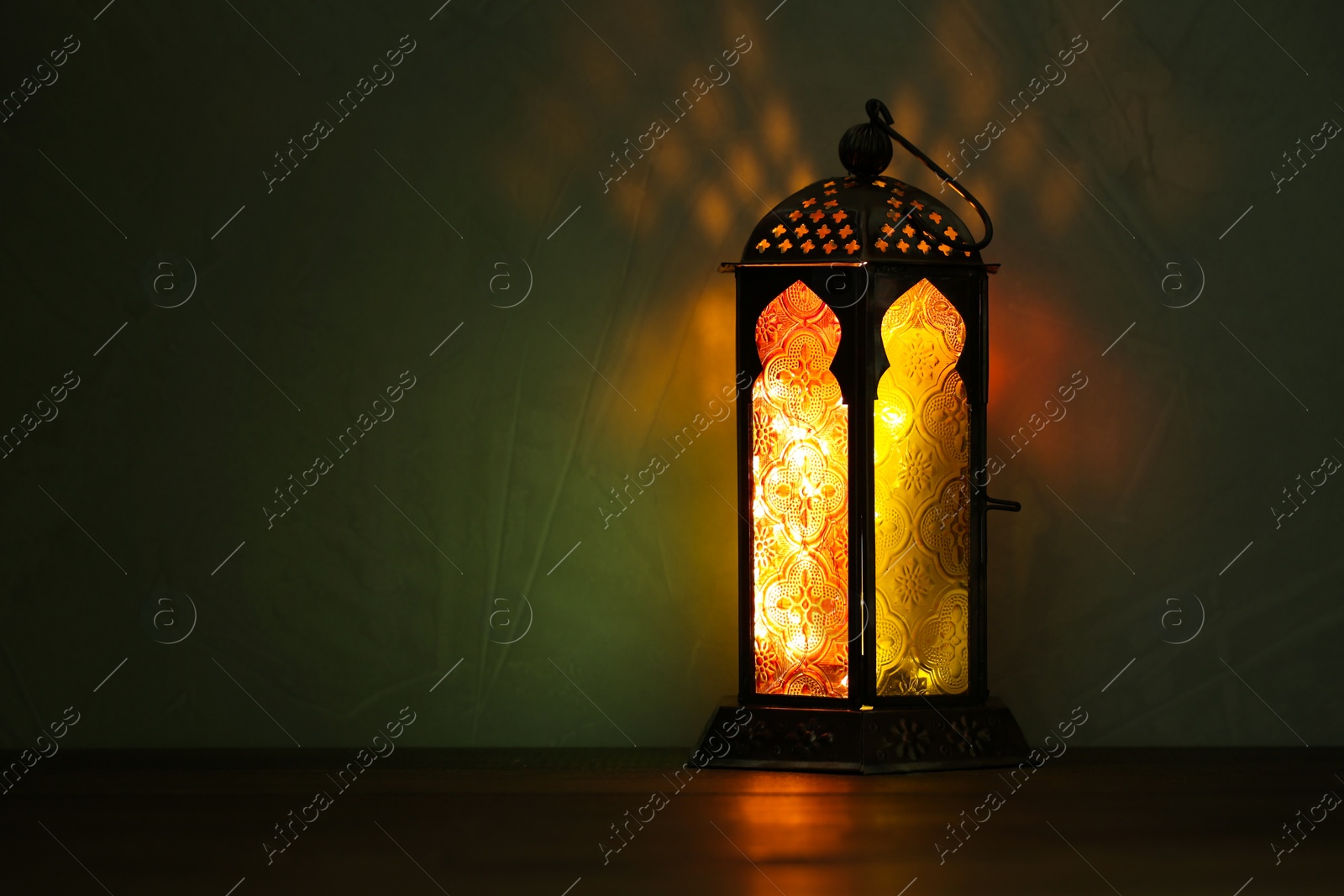 Photo of Decorative Arabic lantern on table against dark background. Space for text