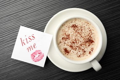 Image of Paper with phrase KIss Me and coffee on black wooden table, flat lay