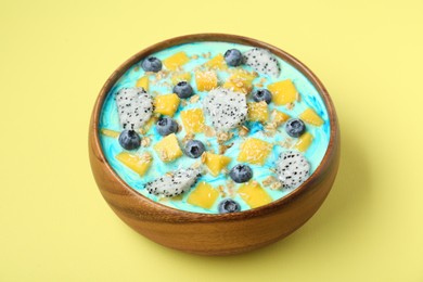 Delicious smoothie bowl with fresh fruits, blueberries and oatmeal on yellow background, closeup