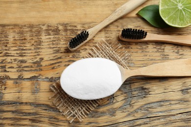 Bamboo toothbrushes, lemon and spoon of baking soda on wooden table, flat lay