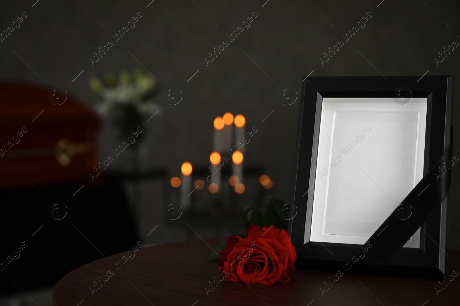 Photo of Black photo frame and red rose on table in funeral home