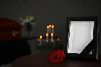 Black photo frame and red rose on table in funeral home