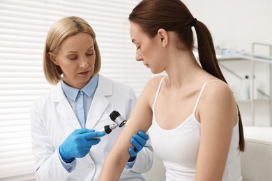 Dermatologist with dermatoscope examining patient in clinic