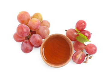 Organic red grapes, seeds and bowl of natural essential oil on white background, top view