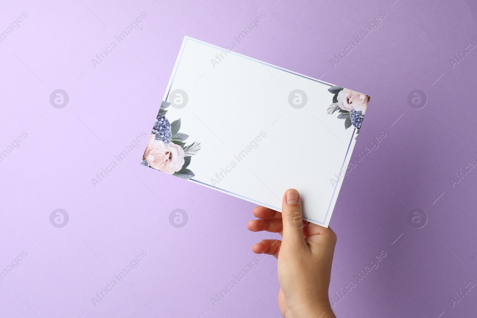 Photo of Woman holding blank invitation card on lilac background, closeup. Space for text