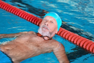 Photo of Sportive senior man in indoor swimming pool