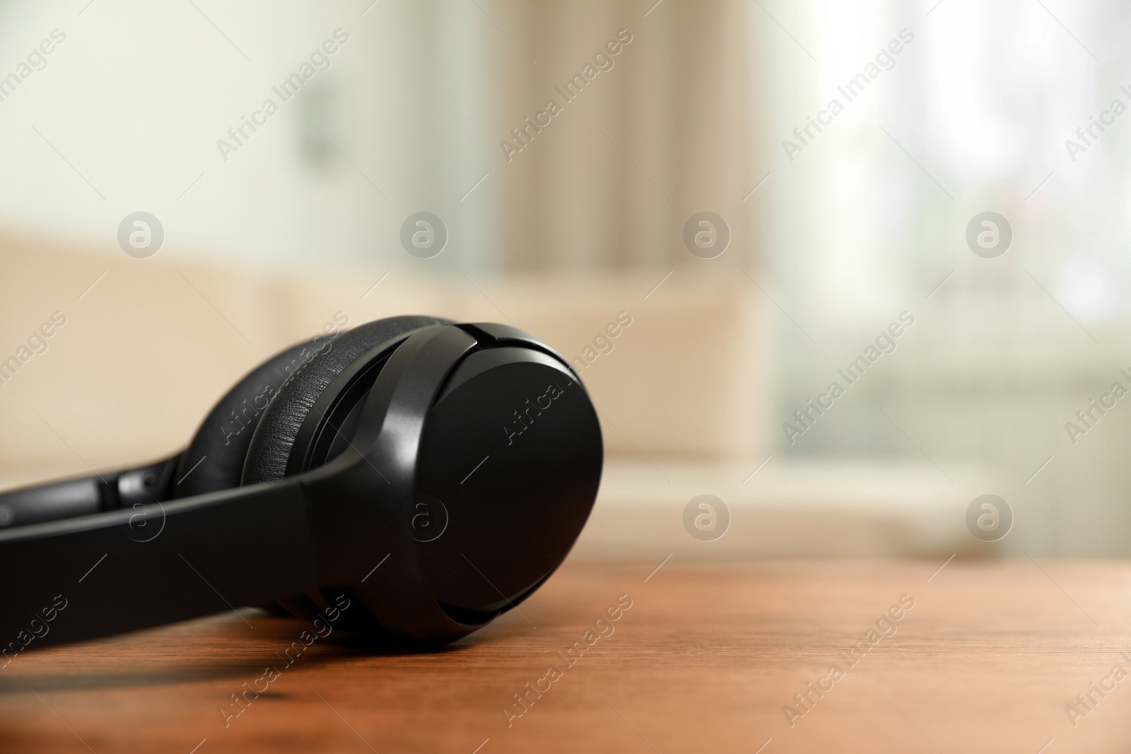 Photo of Modern wireless headphones on wooden table indoors, closeup. Space for text