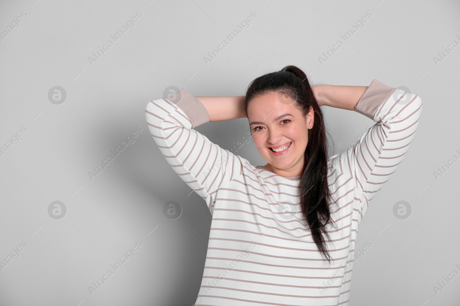 Photo of Beautiful overweight woman with charming smile on light grey background. Space for text