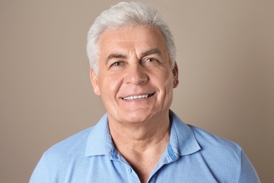 Mature man with healthy teeth on color background