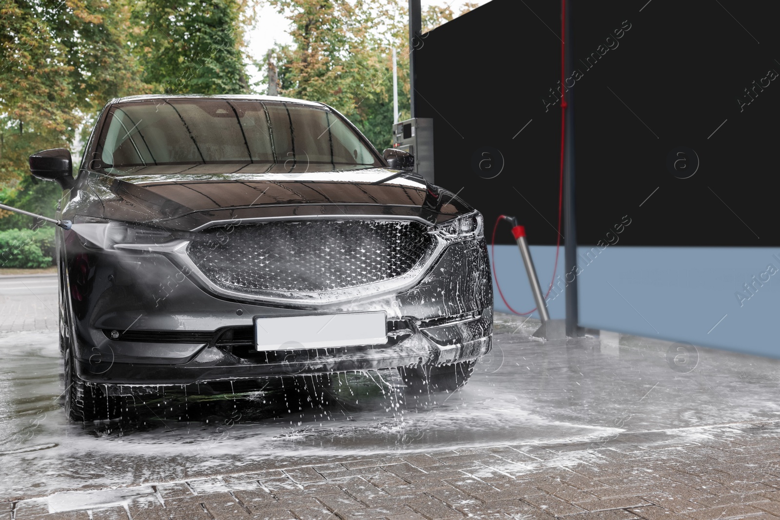 Photo of Washing auto with high pressure water jet at outdoor car wash