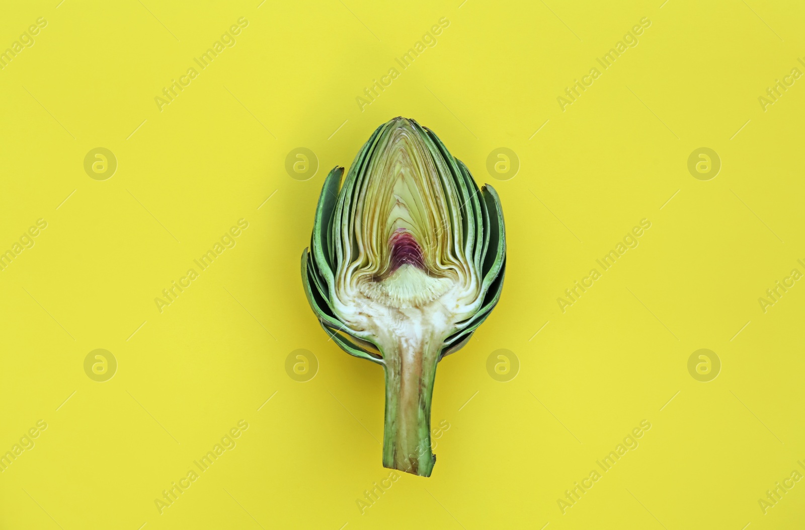 Photo of Cut fresh raw artichoke on yellow background, top view