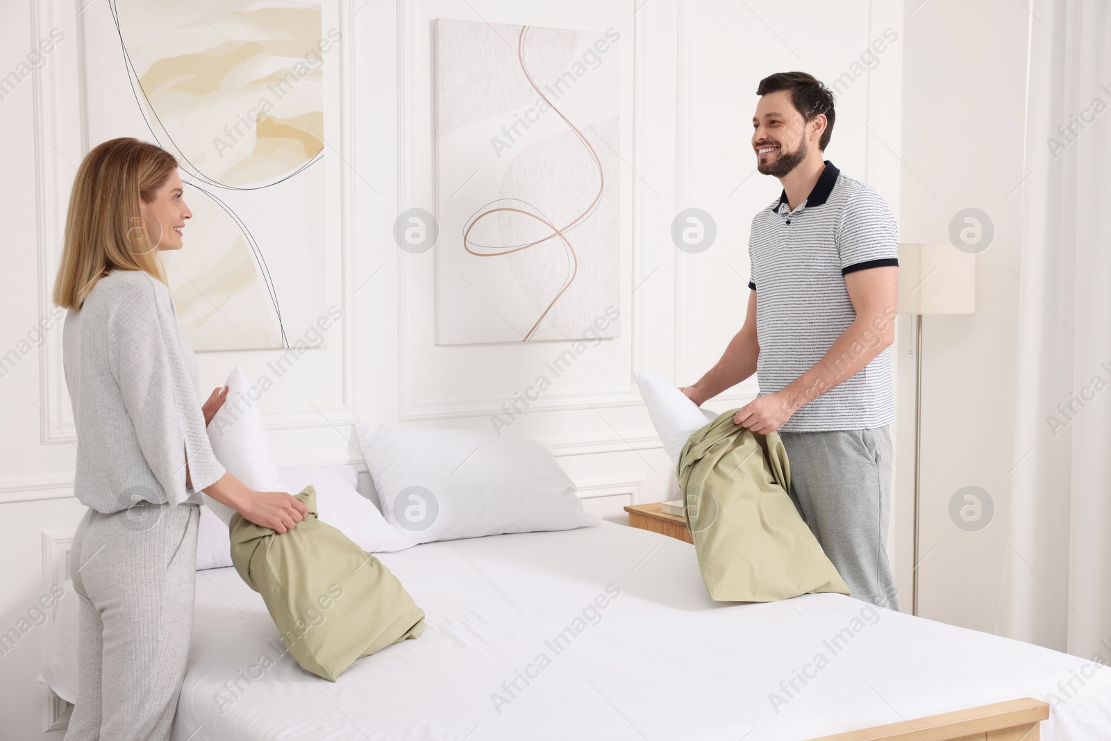 Photo of Couple changing bed linens at home. Domestic chores