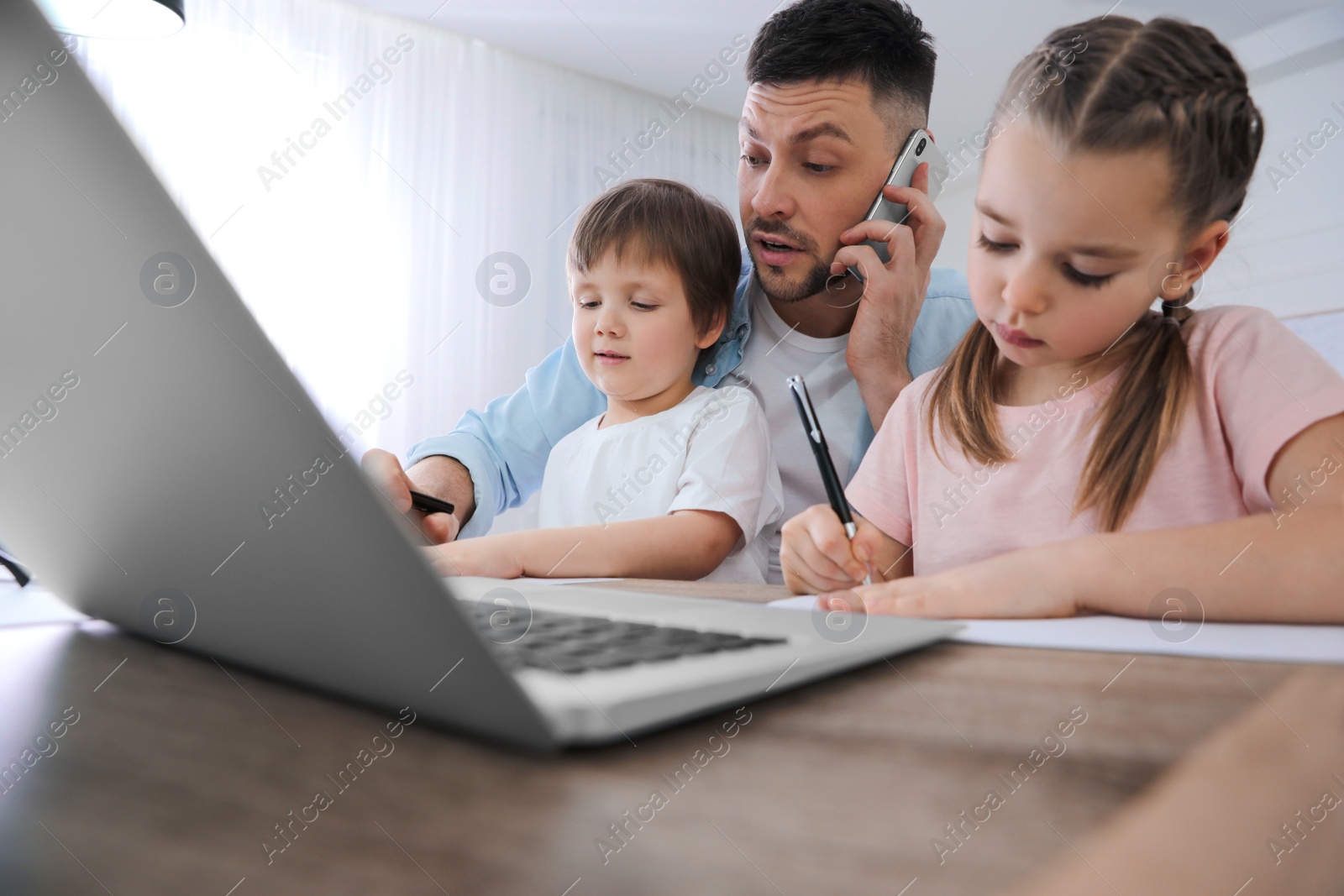 Photo of Overwhelmed man combining parenting and work at home