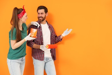 Photo of Happy designers with painting equipment near freshly painted orange wall, space for text