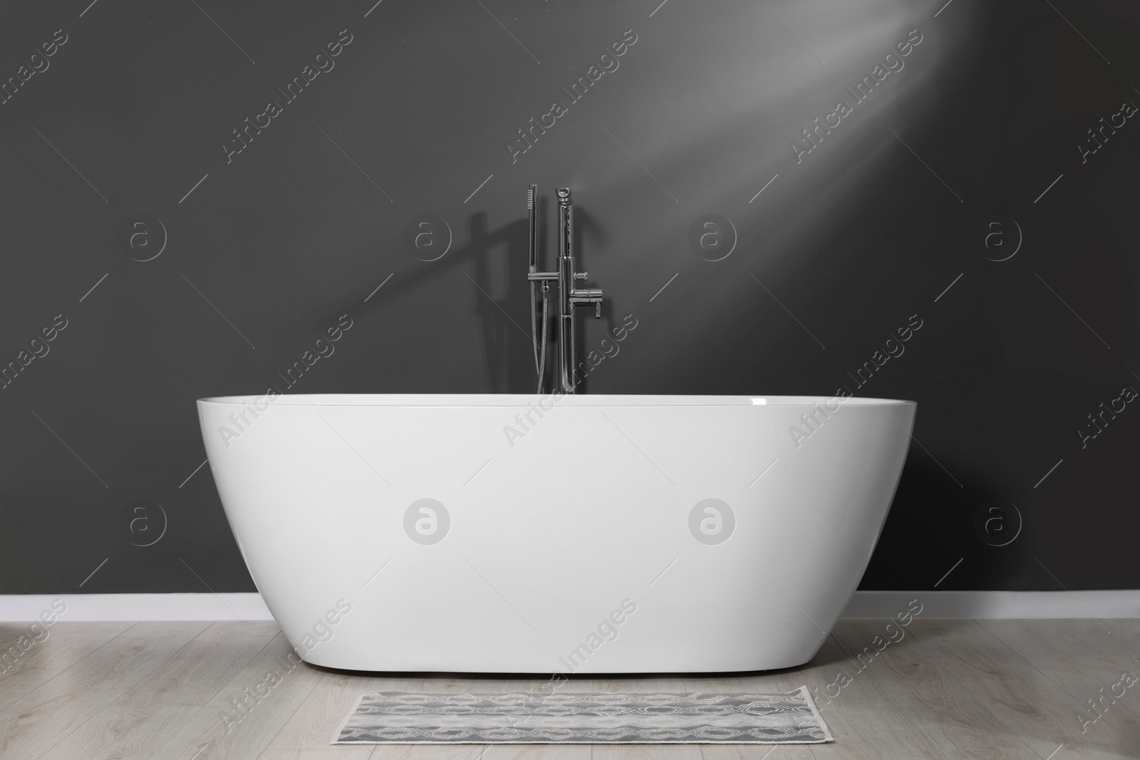 Photo of Stylish ceramic tub near grey wall in bathroom