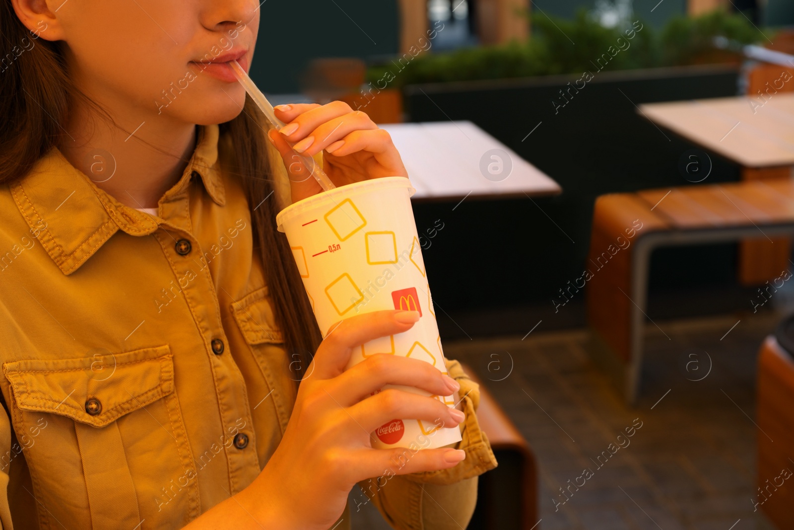 Photo of MYKOLAIV, UKRAINE - AUGUST 11, 2021: Woman with cold McDonald's drink in outdoor cafe, closeup