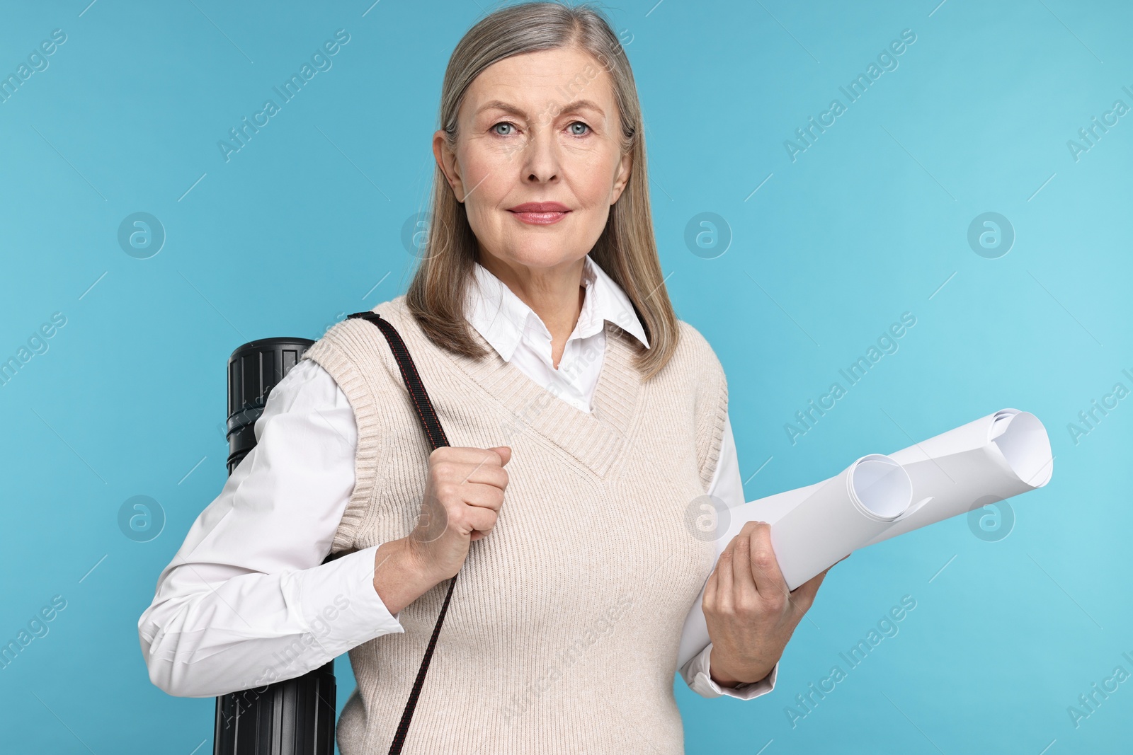 Photo of Architect with drafts and tube on light blue background