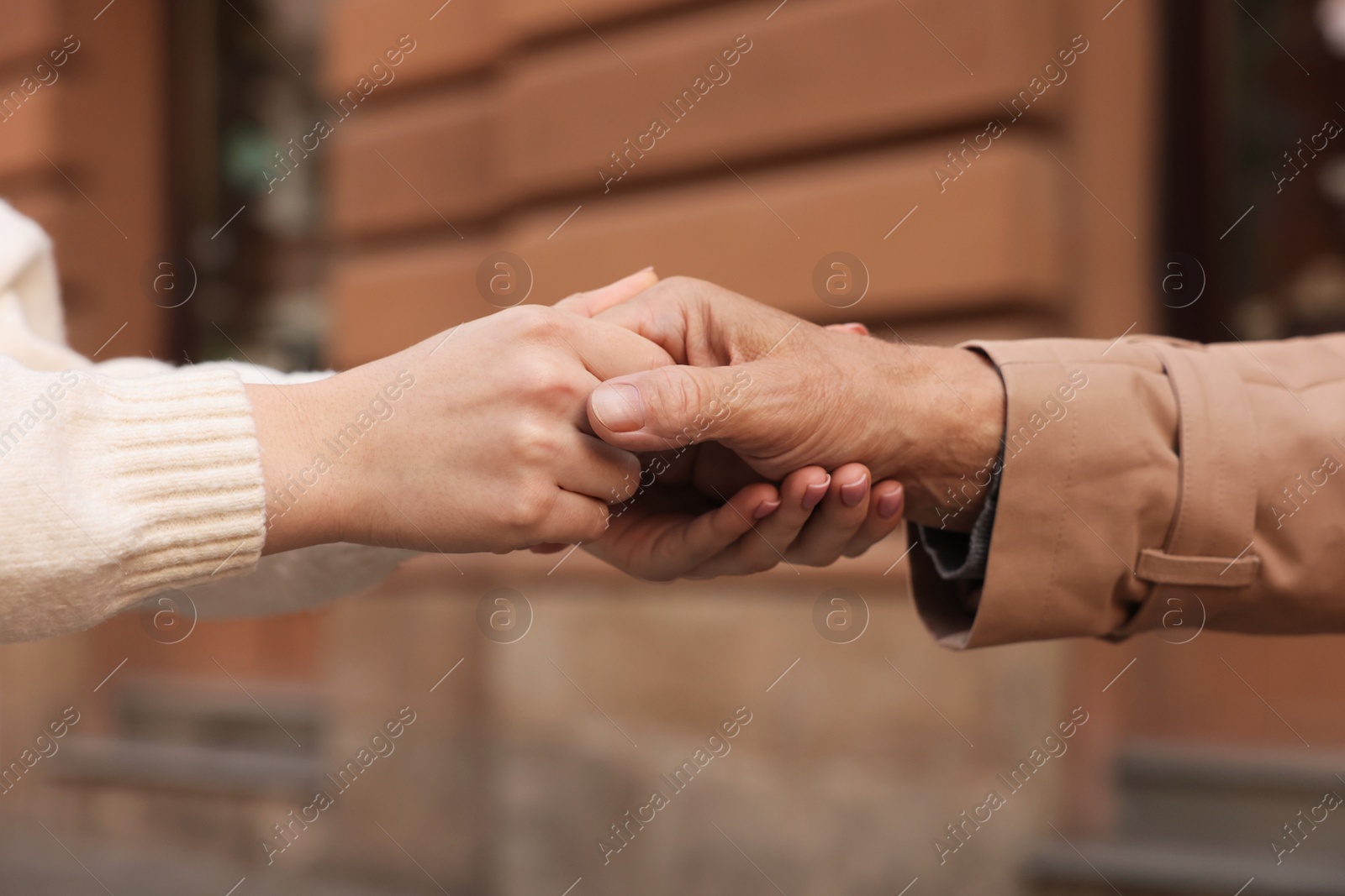 Photo of Trust and support. People joining hands outdoors, closeup