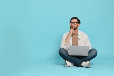 Photo of Handsome man with laptop sitting on light blue background
