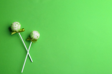 Photo of Tasty cake pops on green background, flat lay. Space for text