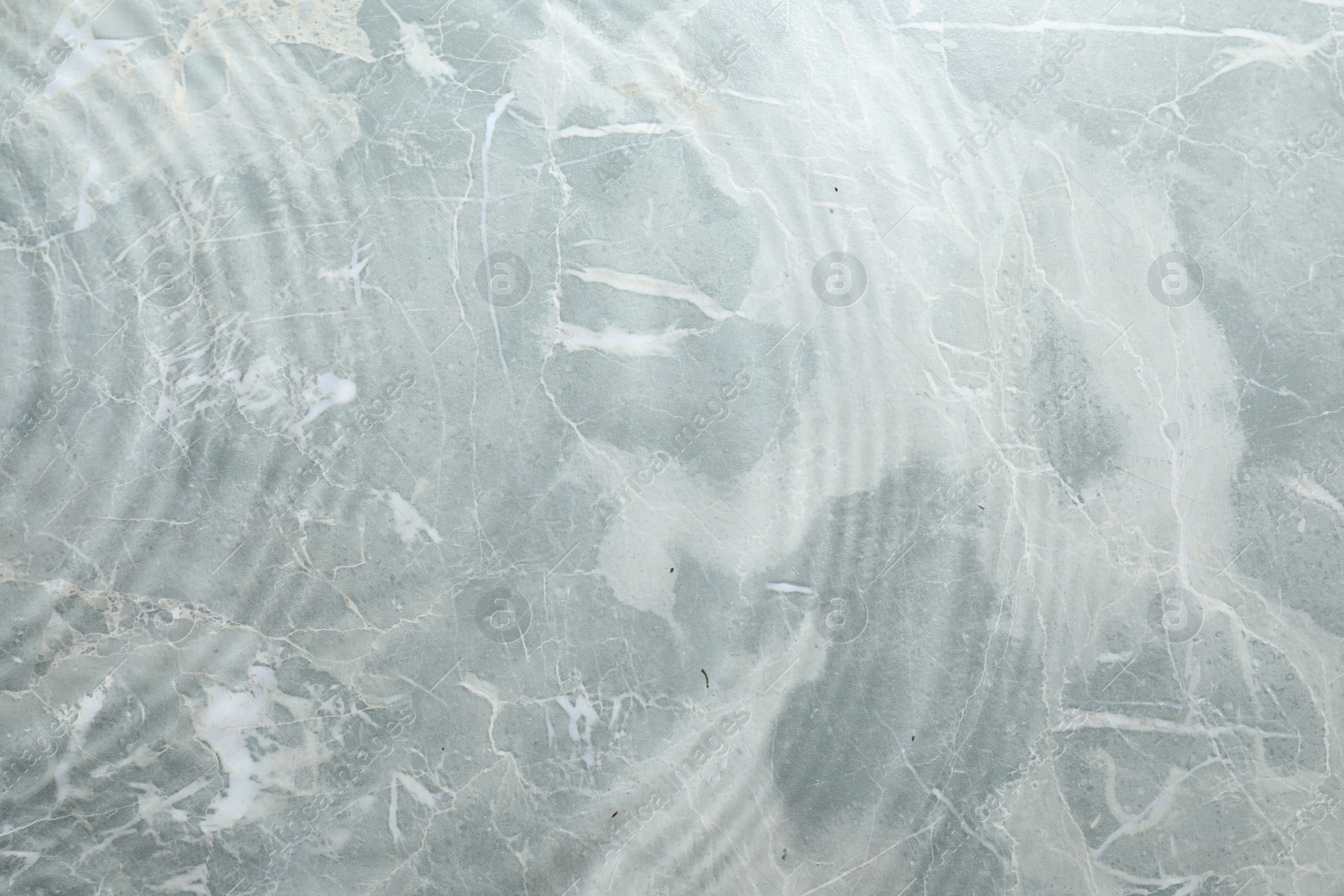 Photo of Rippled surface of clear water on light grey textured background, top view