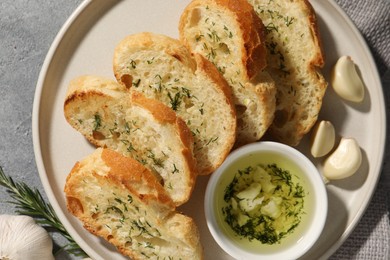Photo of Tasty baguette with garlic and dill served on grey textured table, top view