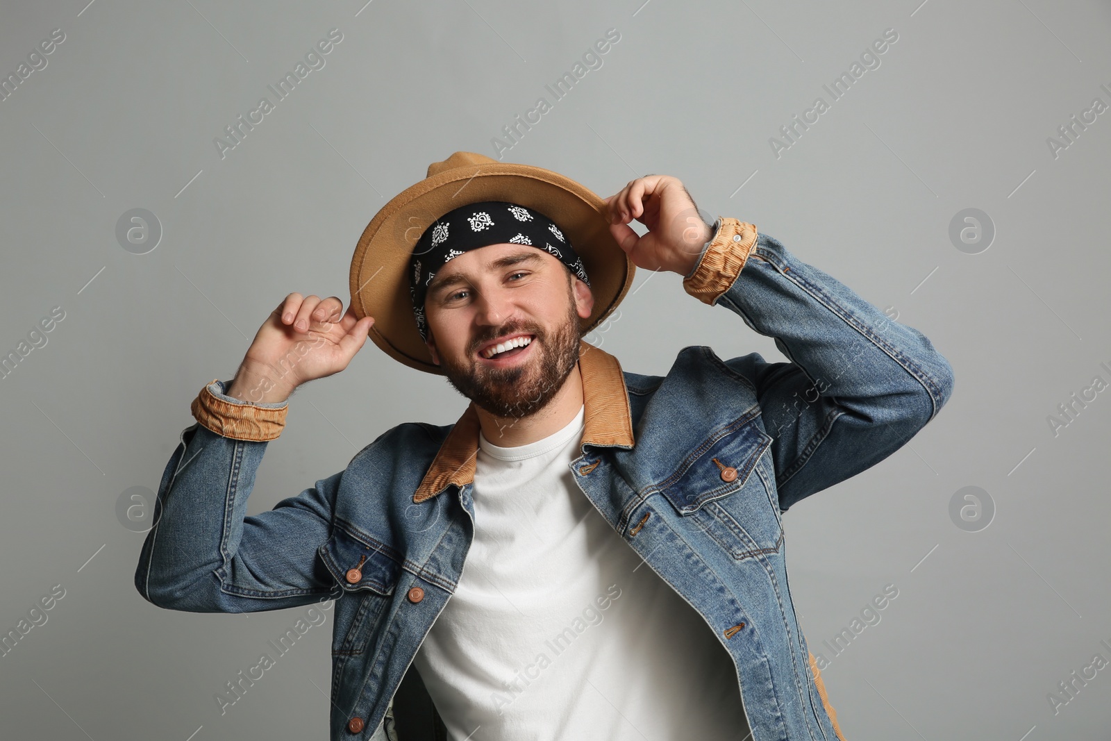 Photo of Fashionable young man in stylish outfit with bandana on grey background