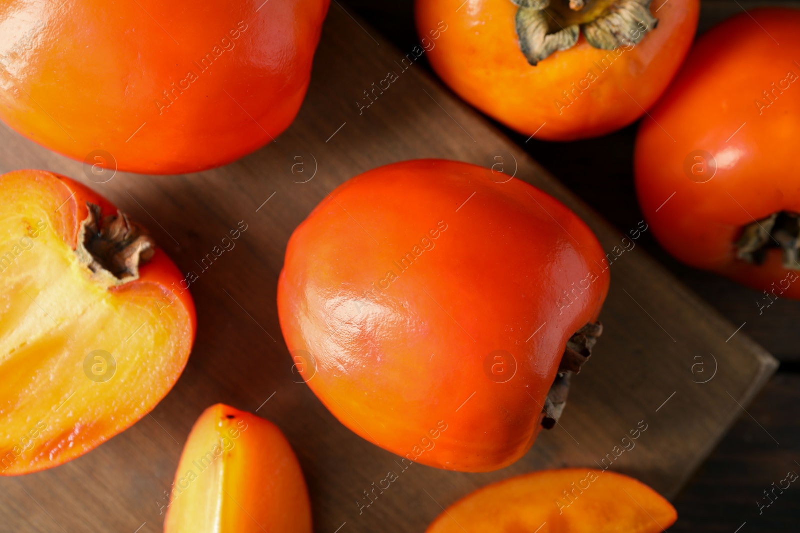 Photo of Delicious ripe persimmons on wooden table, top view