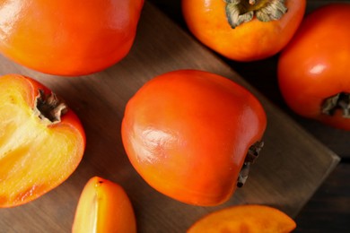 Photo of Delicious ripe persimmons on wooden table, top view