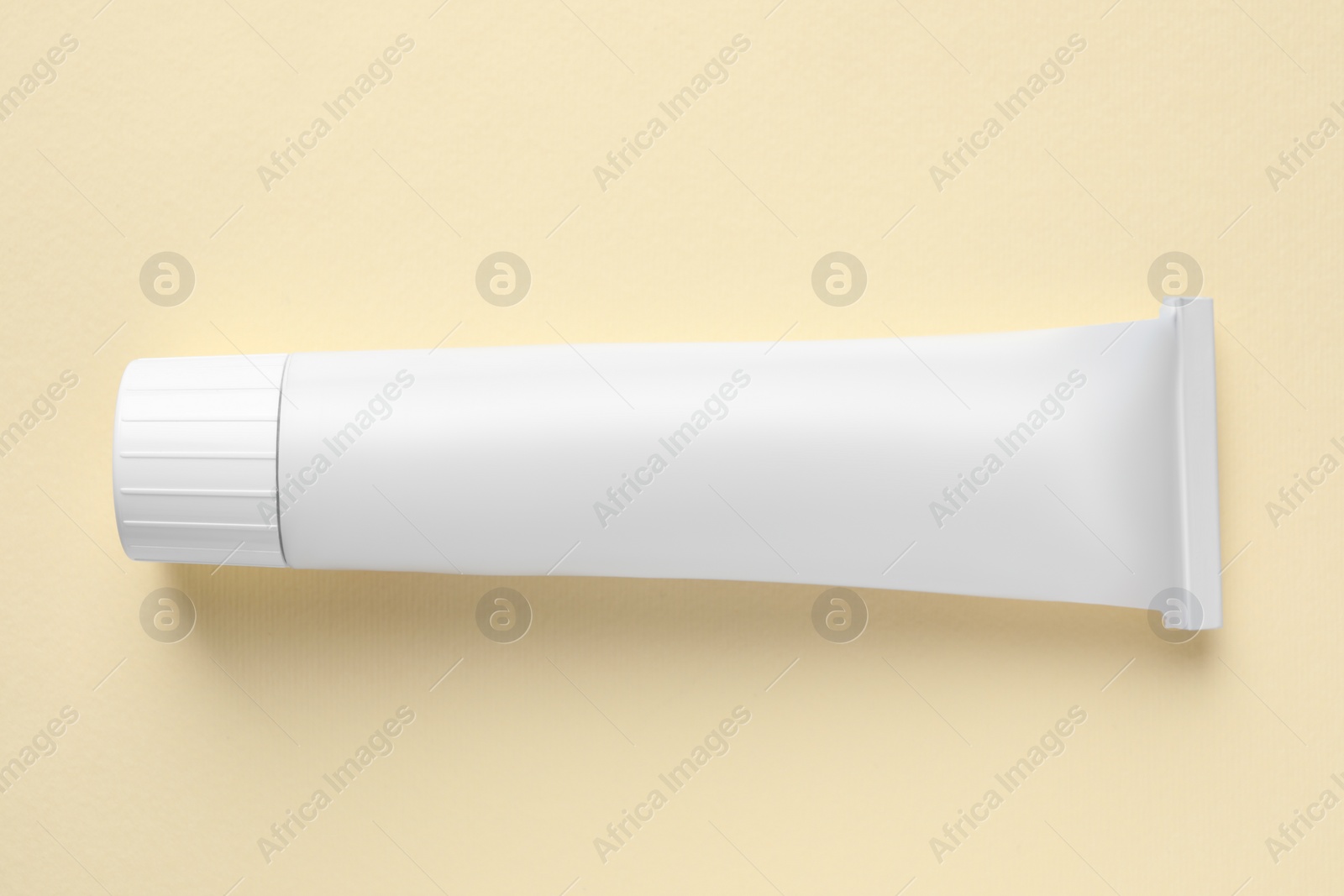 Photo of Tube of ointment on beige background, top view. Space for text