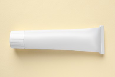 Tube of ointment on beige background, top view. Space for text