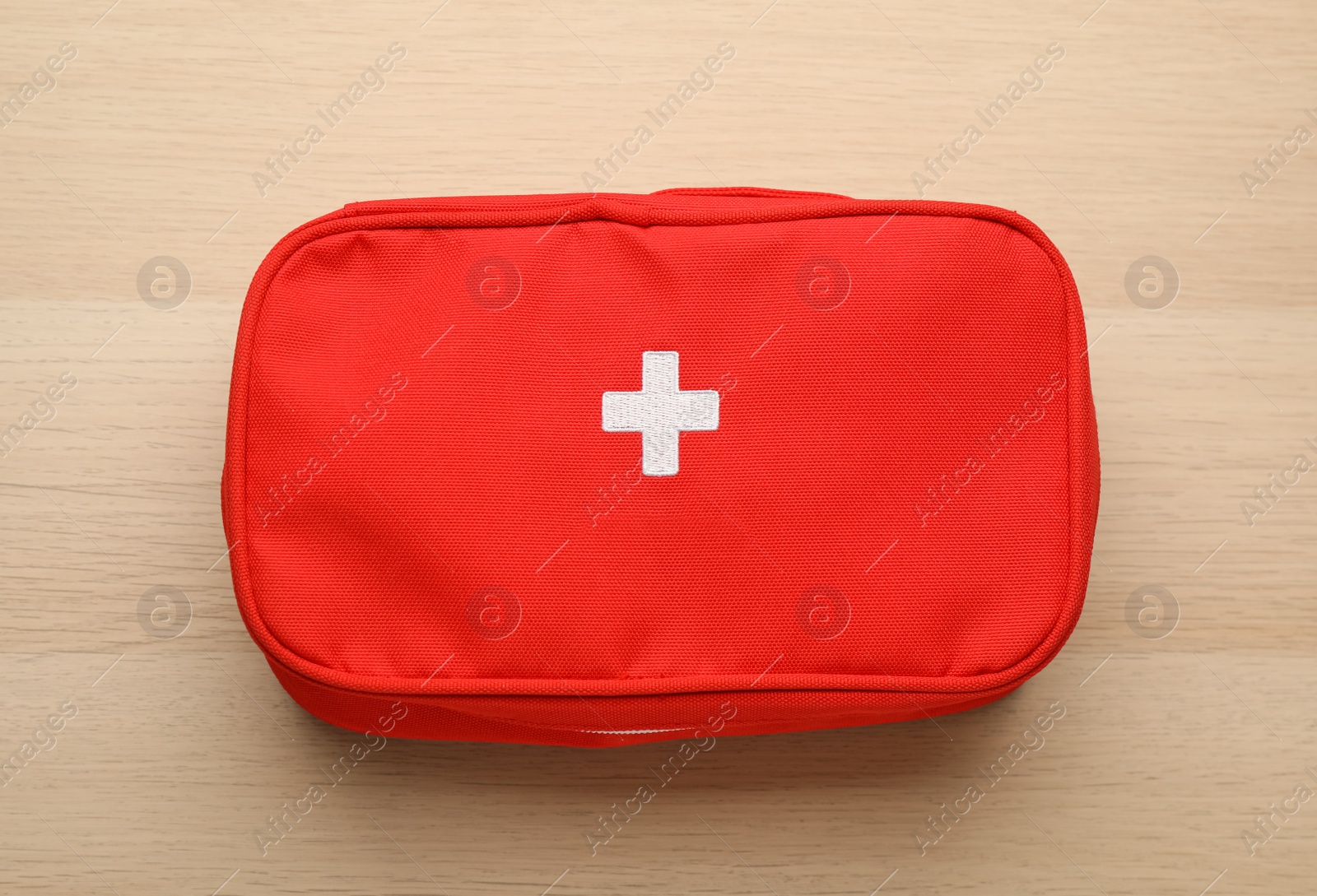 Photo of First aid kit bag on wooden table, top view. Health care