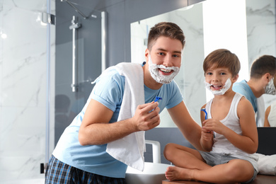 Photo of Dad and son with shaving foam on their faces in bathroom