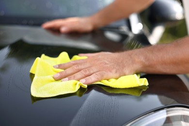 Photo of Man washing car hood with rag outdoors, closeup
