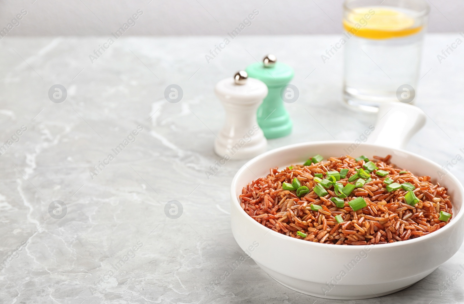 Photo of Tasty brown rice on light grey table. Space for text