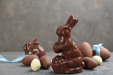 Photo of Chocolate Easter bunny and eggs on grey table. Space for text