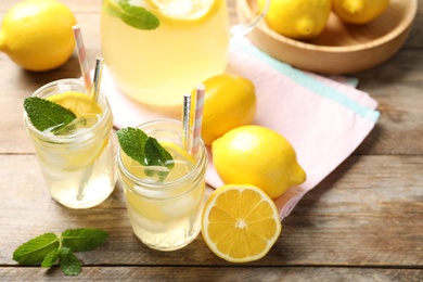 Photo of Natural lemonade with mint and fresh fruits on wooden table. Summer refreshing drink