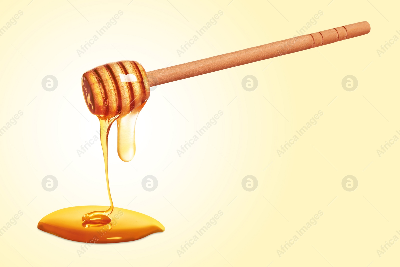 Image of Natural honey dripping from dipper on yellow background